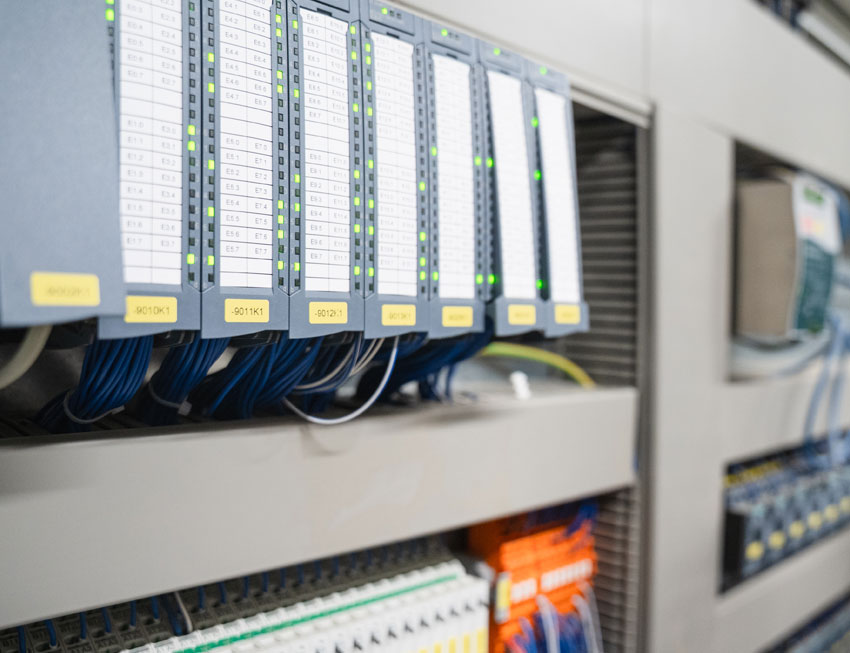 steuerungstechnik-richtig Ein Mann steht an einem Schaltschrank einer Industriemaschine